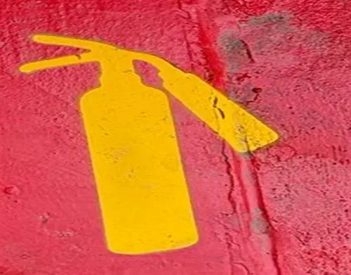 Ícono de extintor pintado en amarillo sobre superficie roja