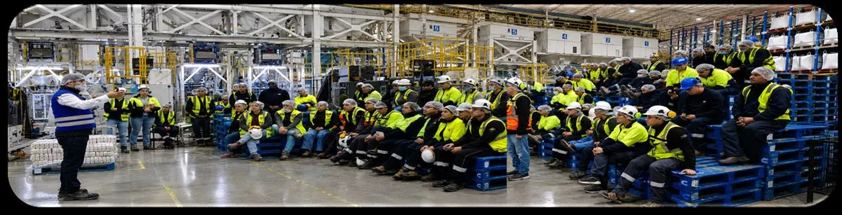 Equipo completo de planta sentado en una capacitación de Lean Training en un galpón industrial